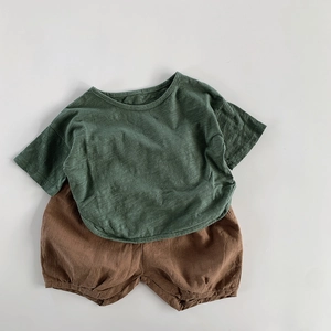 Flat lay of green cotton linen t-shirt and dark brown bloomers for kids summer outfit