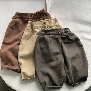 Detail of loose-fit cotton pants for girls in brown, beige, and dark grey tones
