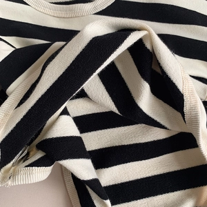 Close-up of black and white striped cotton knit fabric on a girl's casual long sleeve T-shirt
