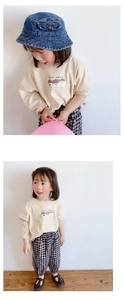 Detalle de camiseta beige de manga larga con setas y pantalones de cuadros para niña
