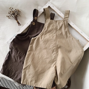 Detail of cotton linen toddler overalls in beige and brown with wooden buttons