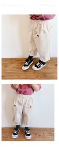 Detail view of cream corduroy pants for girls featuring elastic waist and large button pockets