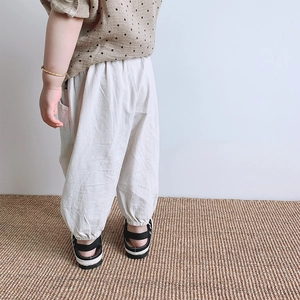 Close-up of kids baggy linen trousers with elastic cuffs in a natural cream white color