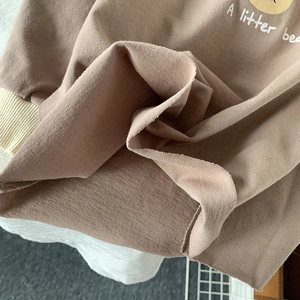 Gros plan sur le tissu en coton marron avec texte d'ours et poignets en maille
