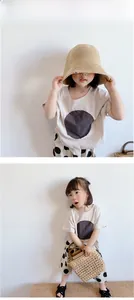 Detail of girl's beige cotton t-shirt with charcoal print and polka dot skirt set