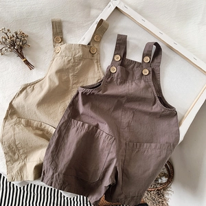 Detail view of cotton kids overalls with wooden buttons and rustic texture