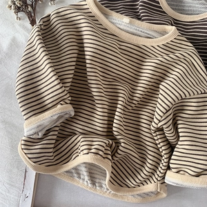 Close-up of beige striped kids' sweatshirt showing textured cotton fabric and ribbed cuffs