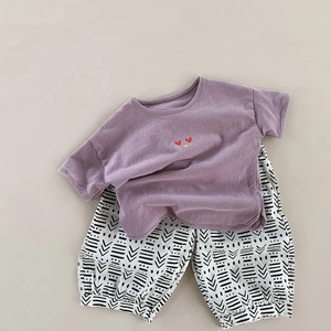Detail of kids summer cotton linen set featuring heart embroidery and tribal shorts