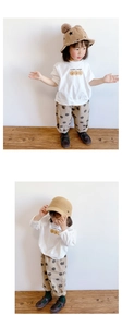 Detalle de camiseta blanca infantil con caritas sonrientes y pantalón de lunares