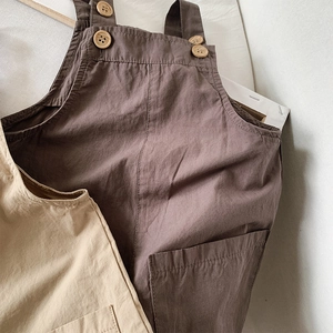 Close-up of breathable cotton fabric and vintage wood buttons on kids overalls