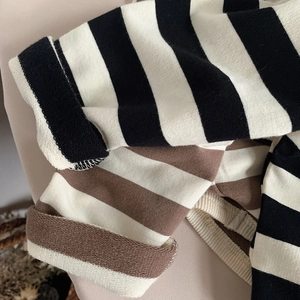Close-up of soft knitted striped cuffs in black and brown showing refined fabric texture