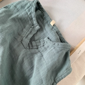 Dettaglio dello scollo a V sul gilet traspirante per bambini in cotone e lino verde