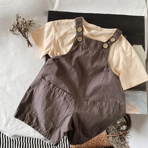 Flat lay of cotton linen summer set with yellow T-shirt and brown buttoned overalls