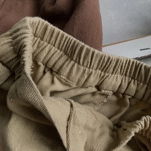 Detail of elastic waistband on khaki and brown toddler trousers in textured cotton fabric