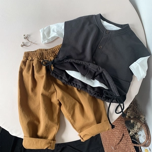 Flat lay of a casual children's set with grey cotton top and yellow trousers