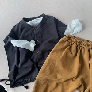 Detailed flat lay of a kids button-up cotton set with charcoal top and ginger pants