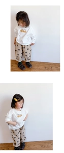 Detalle de camiseta blanca de manga larga y pantalón beige de lunares para niña