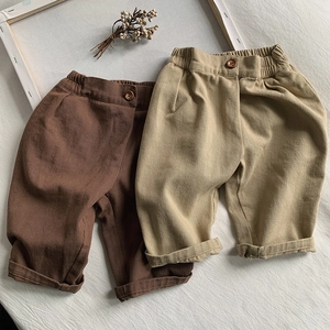 Detail of elastic waist with wood button and texture on toddler cotton trousers