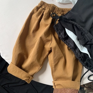 Detail of camel colored kids casual pants with elastic waistband and rolled-up cuffs