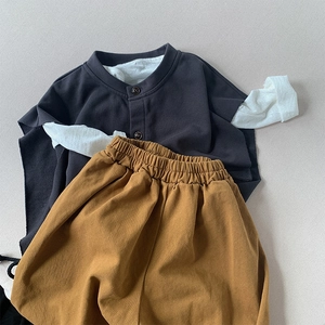 Flat lay detail of a kids' Henley collar layered top and brown elastic waist trousers