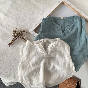 Dettaglio di gilet in cotone e lino per bambini in bianco e ciano con scollo a V