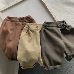 Detail of kids elastic waist trousers in brown, beige and grey with wood button