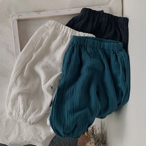 Gros plan de pantalons bouffants en coton et lin noir, blanc et bleu sarcelle texturé