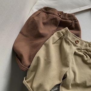 Detail of kids elastic waist cotton pants with button accents in brown and khaki tones