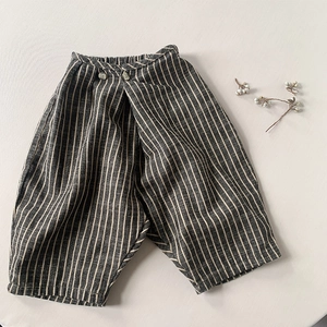 Gros plan du pantalon en coton rayé avec taille asymétrique et boutons décoratifs