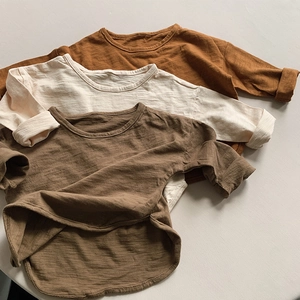 Detailed flat lay of three earthy-toned kids' long-sleeve cotton tees with curved hems