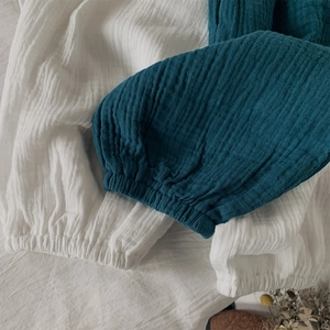 Détail du tissu en gaze de coton respirant et poignets élastiques en blanc et bleu paon