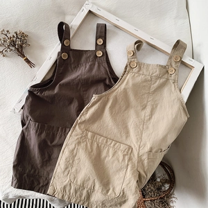 Detailed shot of breathable cotton kids overalls featuring wooden buttons and front pocket
