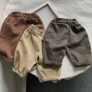 Detail of kids cotton trousers featuring elastic waistbands and wooden buttons in three colors