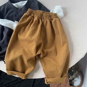 Detail of loose mustard yellow children's cotton pants with elastic waistband and rolled cuffs