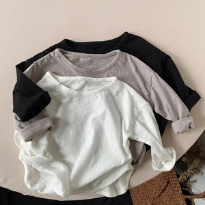 Detail of three long-sleeve cotton t-shirts showing soft slub texture in neutral colors