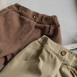 Detailed view of elastic waist and wood buttons on kids thick twill cotton pants