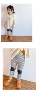 Detail of baby girls' long sleeve bear shirt and black and white striped leggings