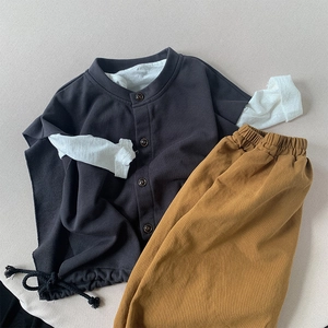 Flat lay of a two-piece kids casual cotton outfit with grey vest and mustard trousers