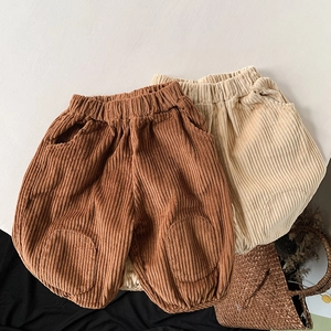 Detail of corduroy kids trousers featuring elastic waist and knee patches in brown and beige
