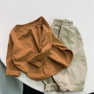 Flat lay of ginger yellow long sleeve cotton t-shirt and beige casual kids trousers