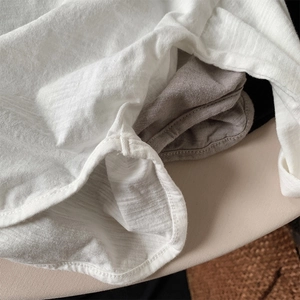 Detailed macro view showing the textured slub cotton fabric and curved hem of the t-shirts