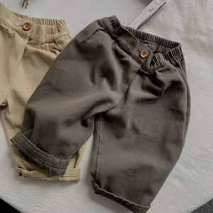 Detail view of cotton kids casual pants featuring elastic waist and wood button accents