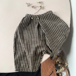 Détail du short en coton et lin à rayures verticales avec boutons et texture naturelle
