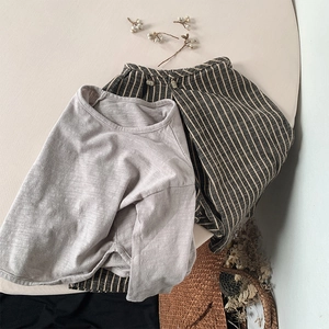 Détail ensemble enfant en coton et lin avec pantalon rayé et t-shirt gris à manches longues