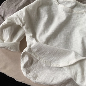 Detail of white slub cotton tee showing curved hem and breathable texture
