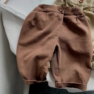 Detailed macro view of girls' loose cotton pants featuring elastic waist and vintage wood button