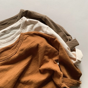 Detail of three slub cotton long sleeve shirts in caramel, cream and olive colors