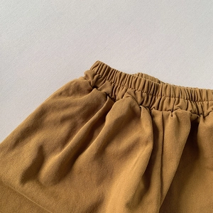 Close-up of caramel cotton kids trousers showing elastic waistband and twill texture