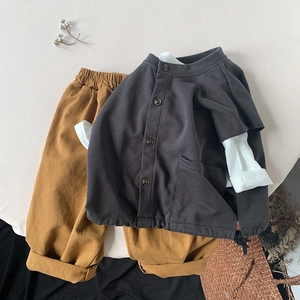 Detail view of dark grey buttoned cardigan and ochre cotton pants for kids