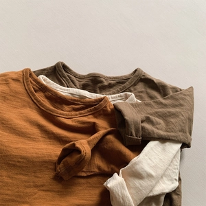 Close-up detail of slub cotton long sleeve t-shirts in earthy tones for kids